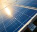 Close-up of monocrystalline solar photovoltaic panel cells showing the grid pattern and blue silicon surface with sun reflection.